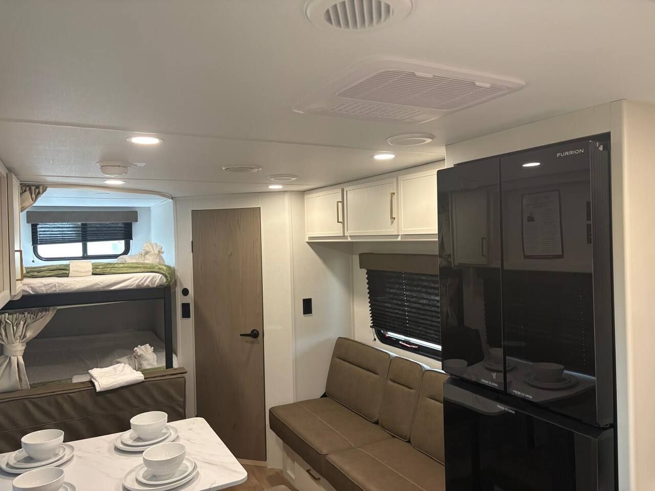 Ein kompaktes Wohnmobil-Interieur mit einer Küchenzeile, einer Essecke und einer Schlafkoje.