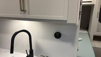 A compact kitchenette with a modern faucet, a small sink, and a built-in ventilation system.