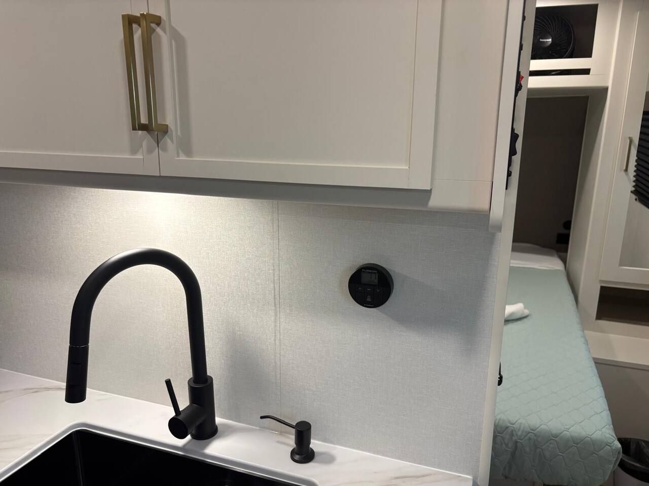 A compact kitchenette with a modern faucet, a small sink, and a built-in ventilation system.