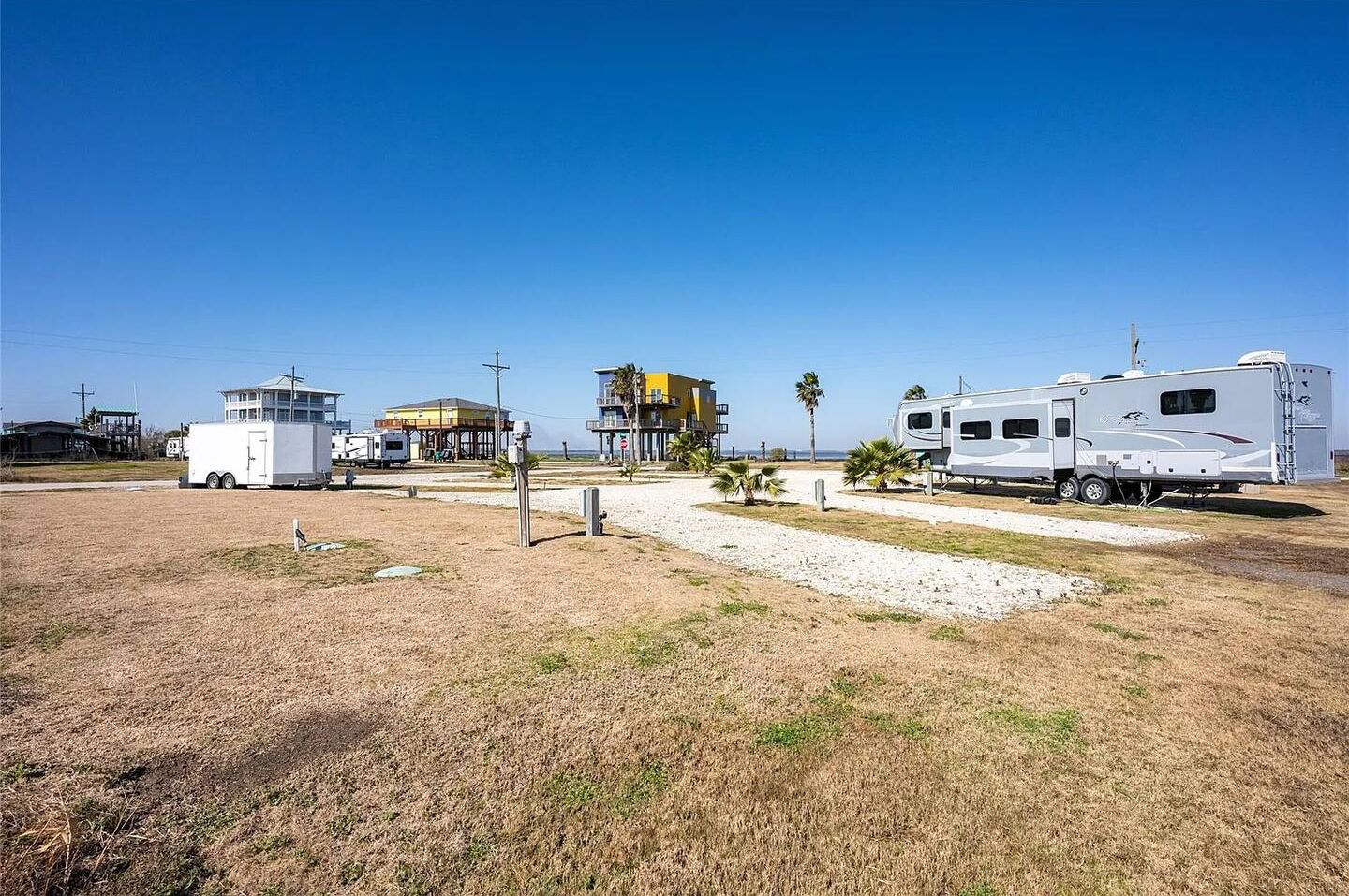 Un camping con vehículos recreativos, un pequeño edificio y cielo despejado.