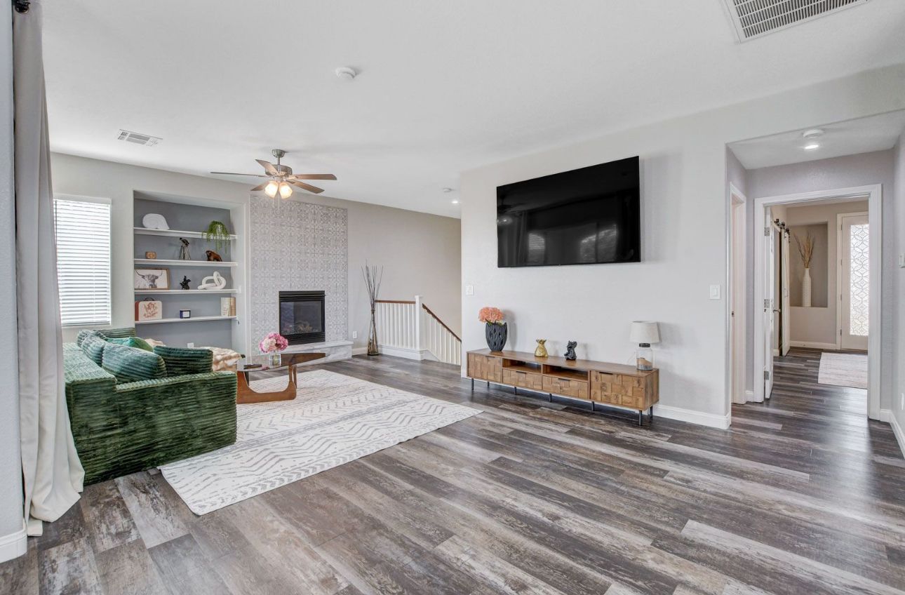 Ein geräumiges Wohnzimmer mit Kamin, einem grünen Sofa, einem Holztisch und einem flachbildfernseher an der Wand.