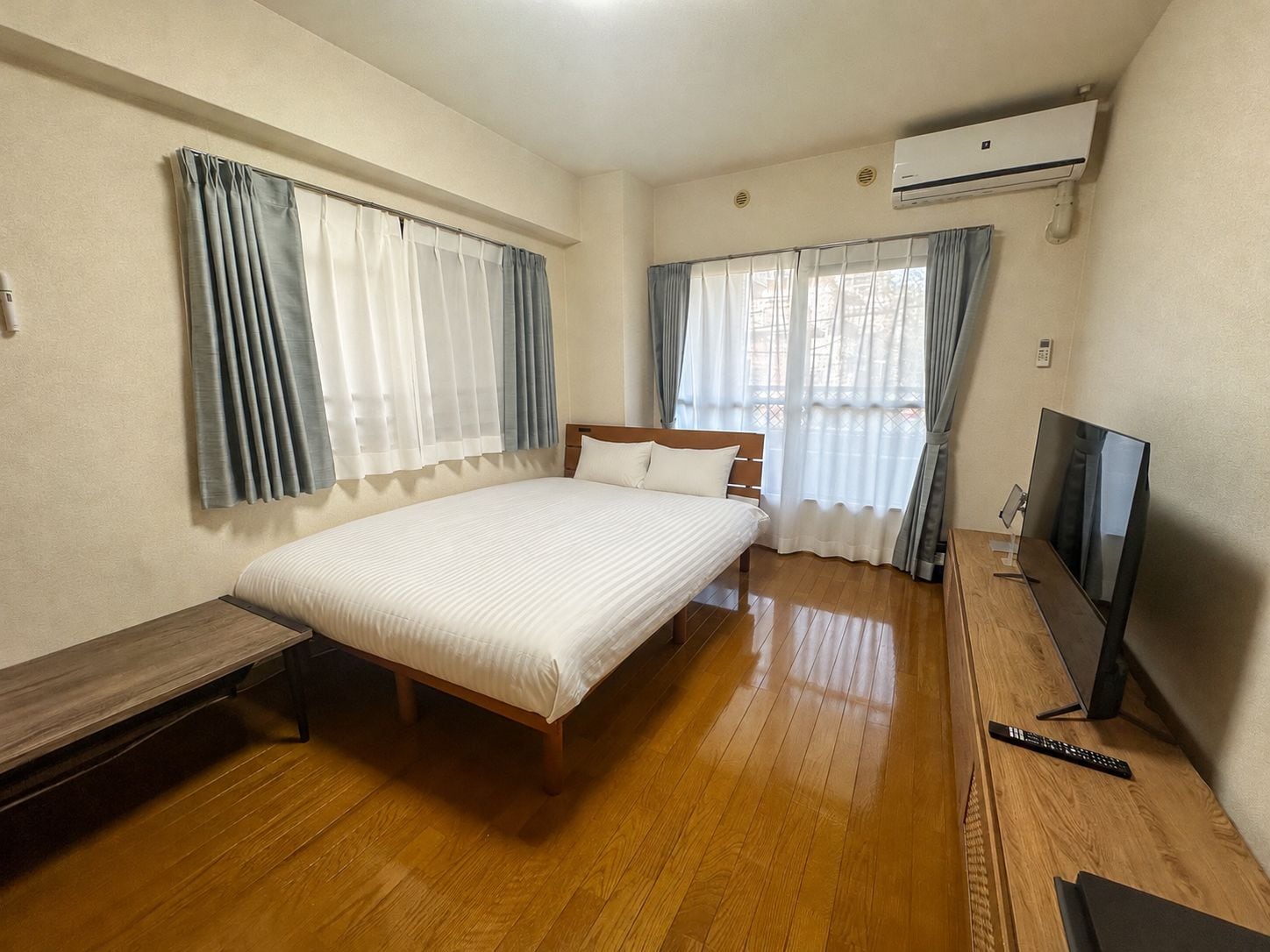 Une chambre d’hôtel avec un lit, une télévision, un bureau et une fenêtre avec des rideaux.