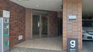 A building entrance with a vending machine, a glass door, and a sign for 'goom MINOSHIMA'.
