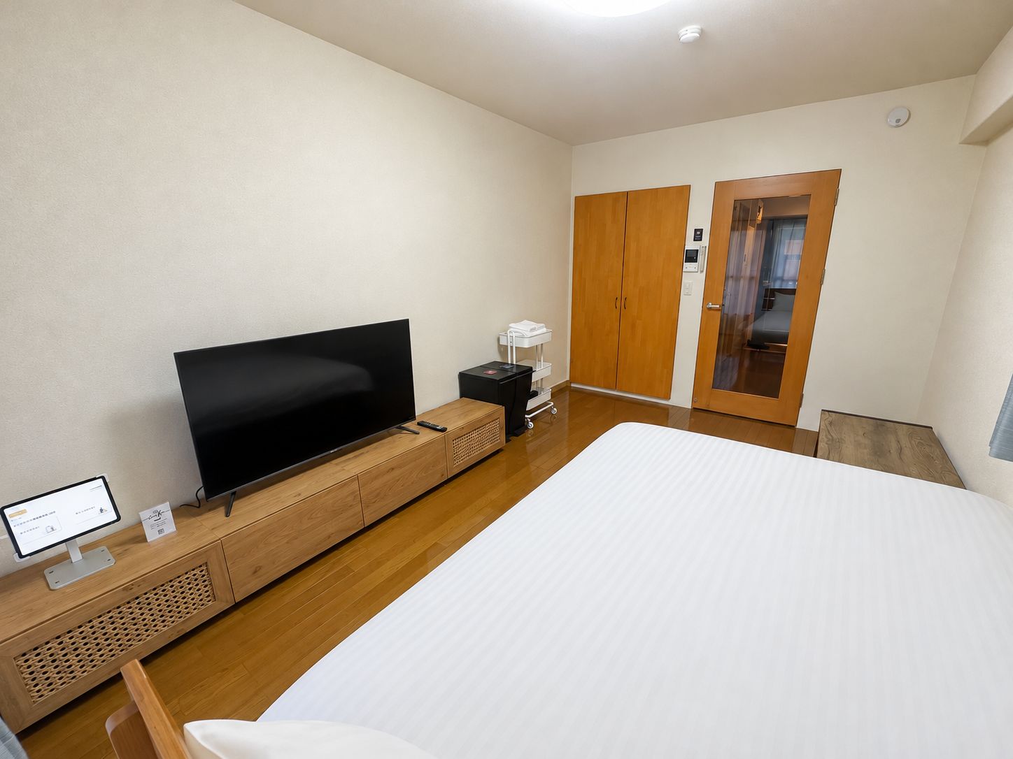 A hotel room with a bed, a TV, a desk with a computer, a wardrobe, and a bathroom.