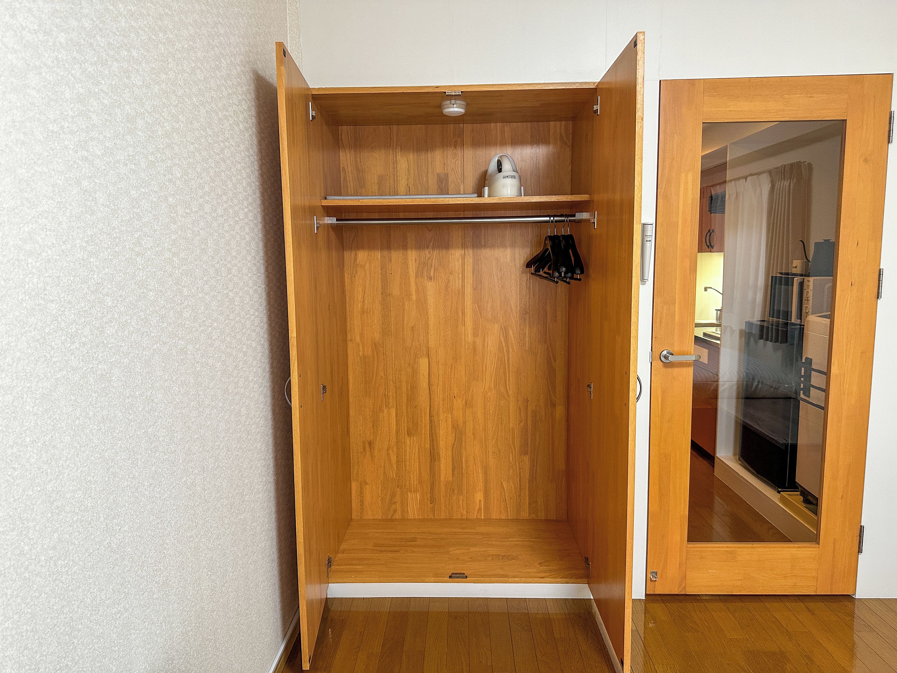 Un armario de madera con barra para colgar y un pequeño estante.