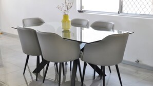 A modern dining area with a glass table surrounded by four grey chairs with black legs. - Modern Home near Swan Valley (Beechboro)