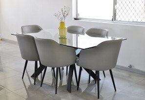 A modern dining area with a glass table surrounded by four grey chairs with black legs. - Modern Home near Swan Valley (Beechboro)