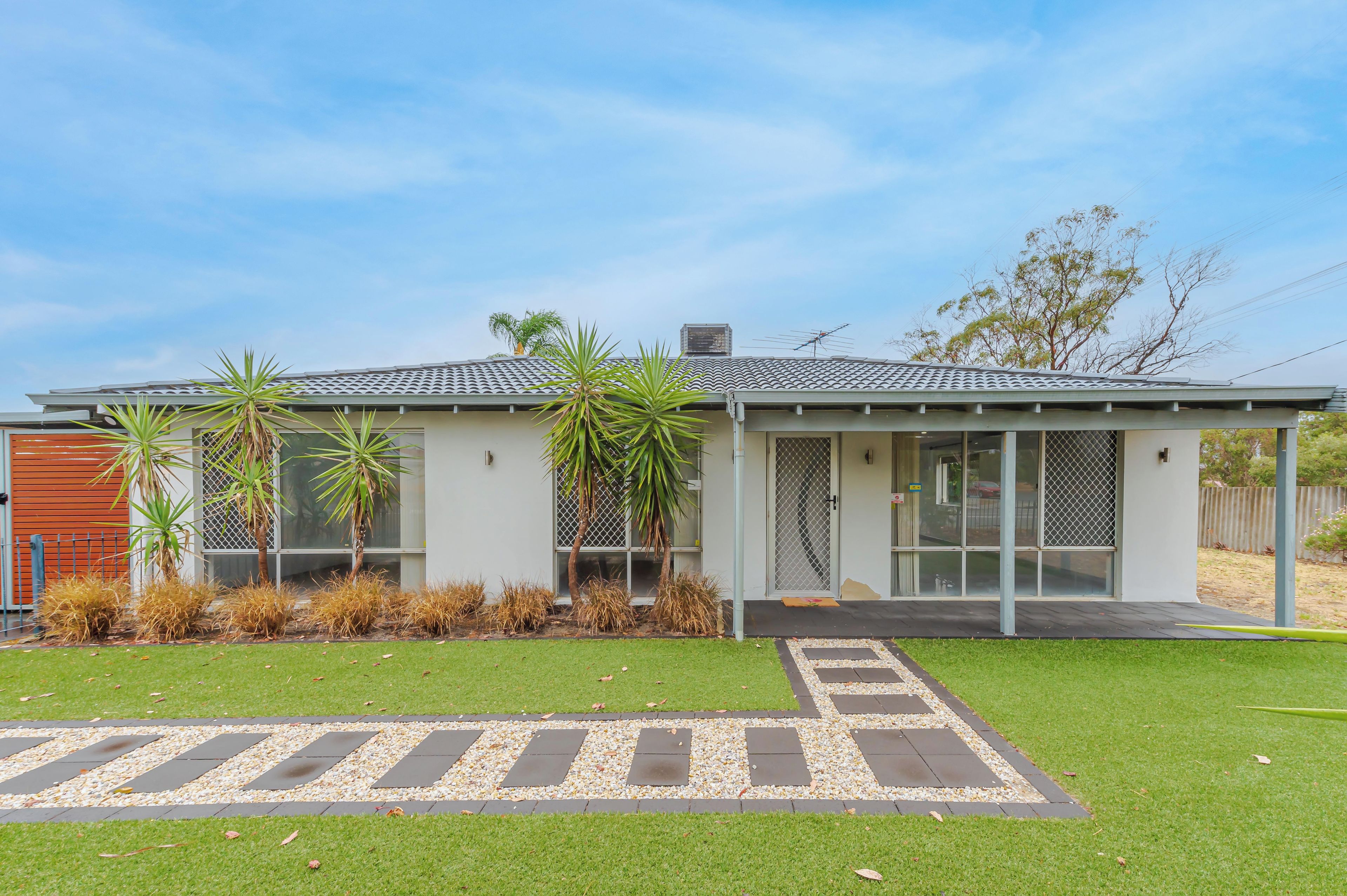 A modern two-story house with a flat roof, large windows, and a well-maintained lawn.