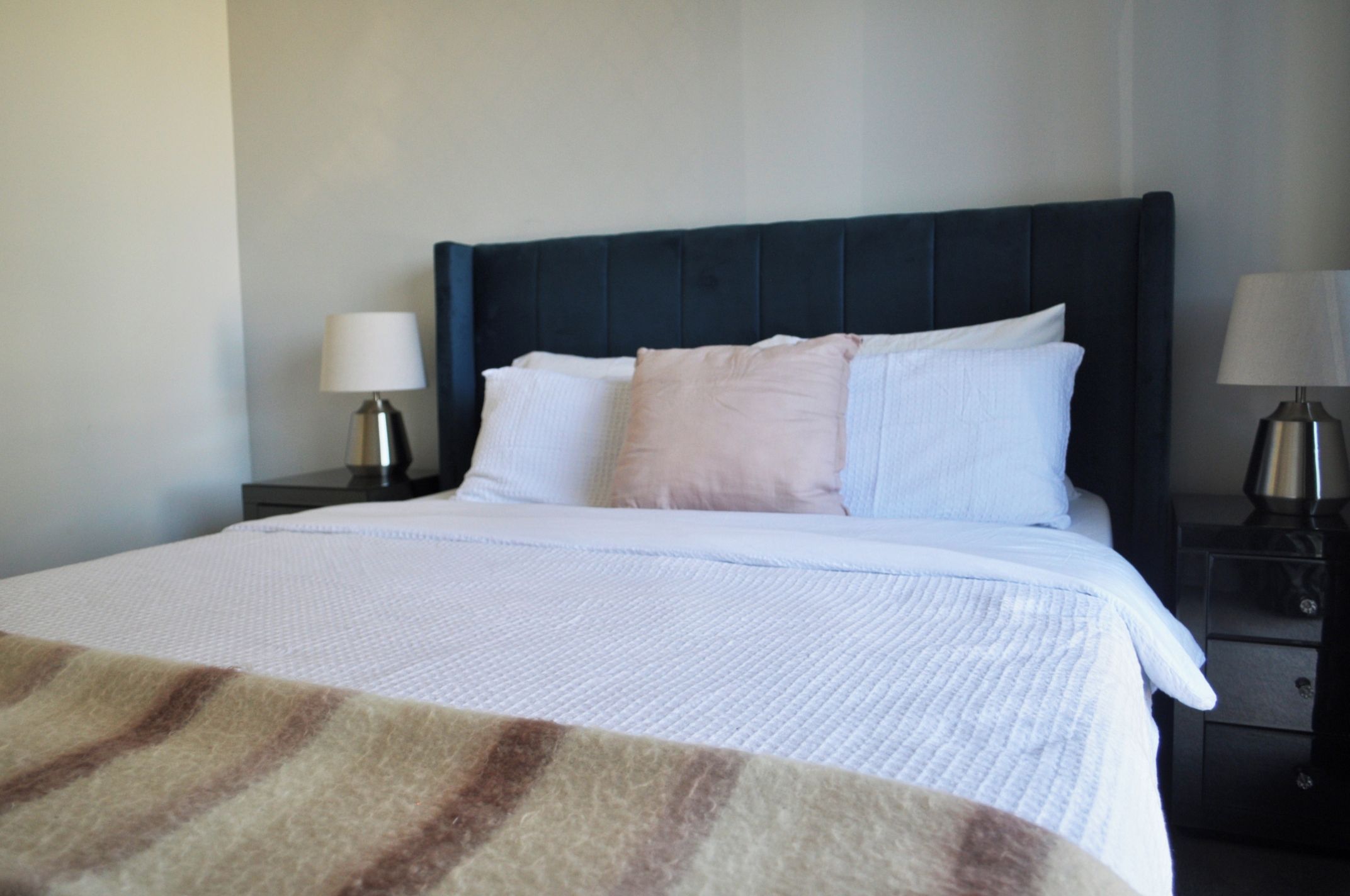 A hotel room with a bed, two bedside tables, and a nightstand.