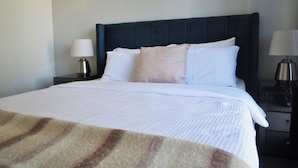 A hotel room with a bed, two bedside tables, and a nightstand. - Modern Home near Swan Valley (Beechboro)
