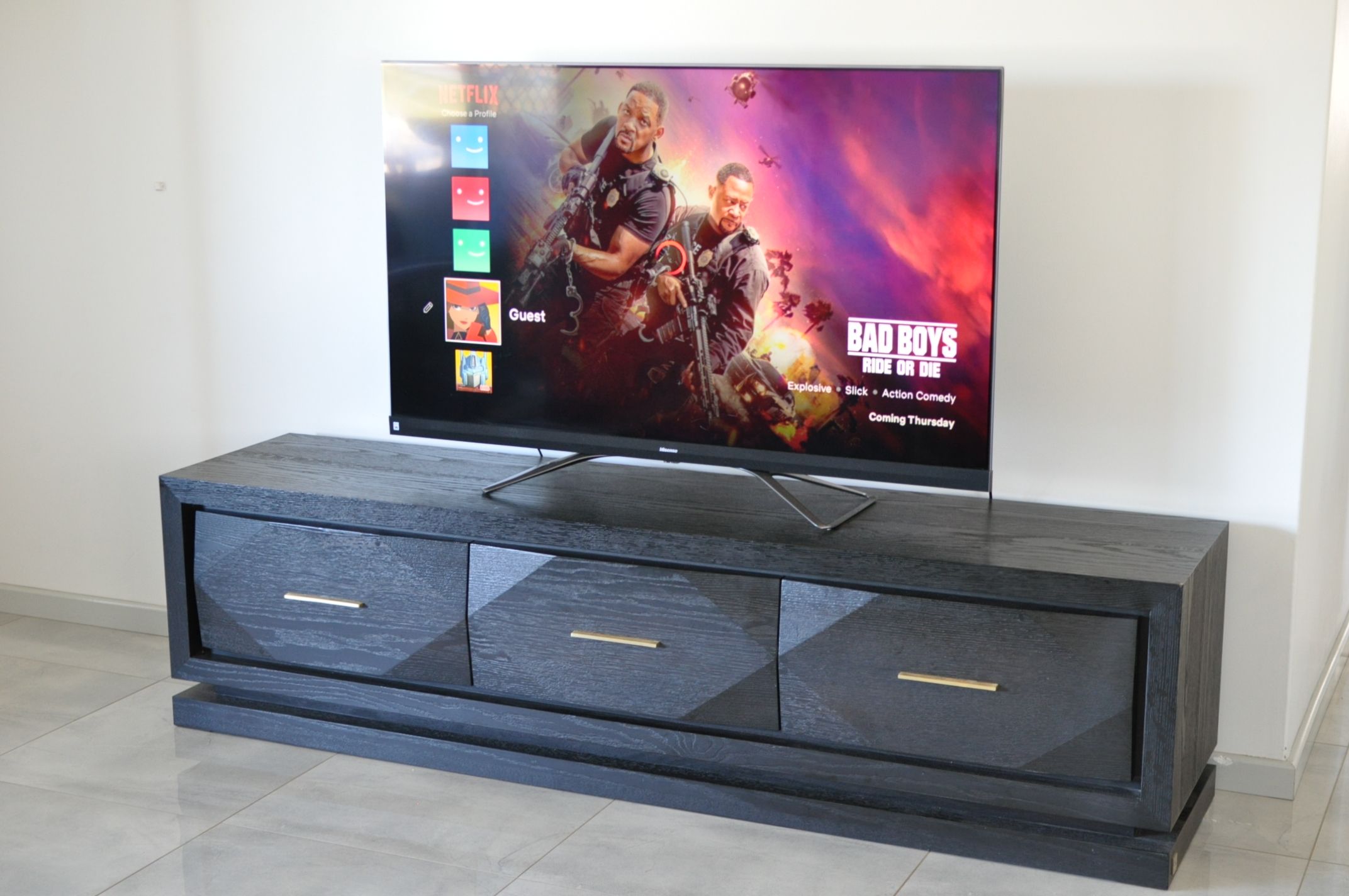 Un televisor de pantalla plana sobre un mueble bajo de madera oscura con tres cajones.