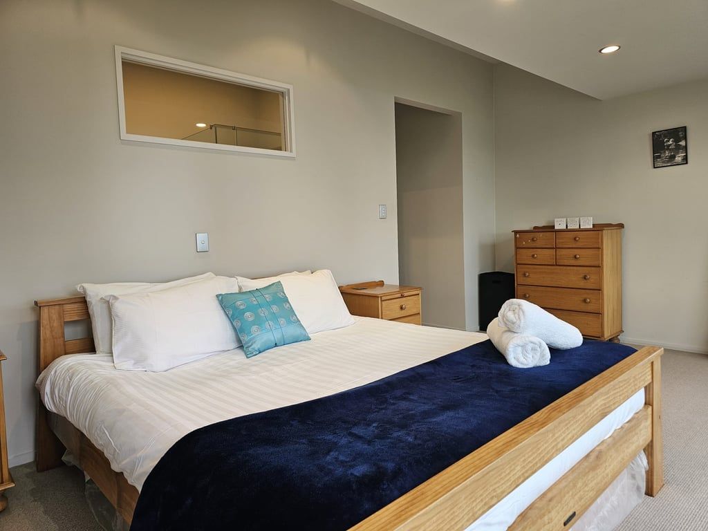 A bedroom with a bed, a dresser, a nightstand, and a mirror.