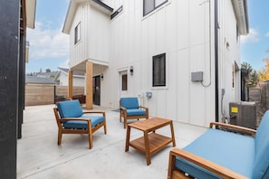 Ein Wohngebäude mit Terrasse, ausgestattet mit Holzmöbeln und einer weißen Fassade.