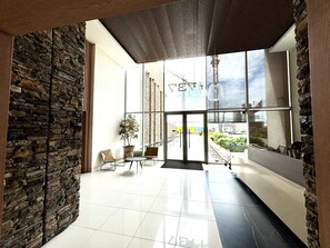 Eine Lobby mit einer Steinwand, einer Topfpflanze und einer Sitzecke mit Sesseln.