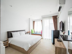 A hotel room with a bed, a desk, a television, and a window with curtains. - Baan I Inspire (Mueang Phrae District)