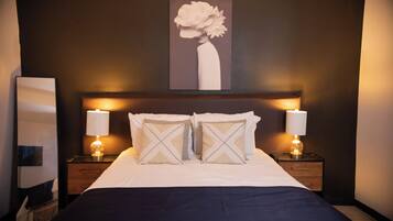 Habitación de hotel con una cama grande, dos lámparas de noche, una obra de arte en la pared y un espejo.