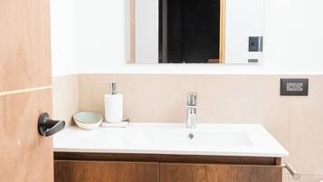 Un baño con tocador de madera, un lavamanos blanco, un espejo y un inodoro.
