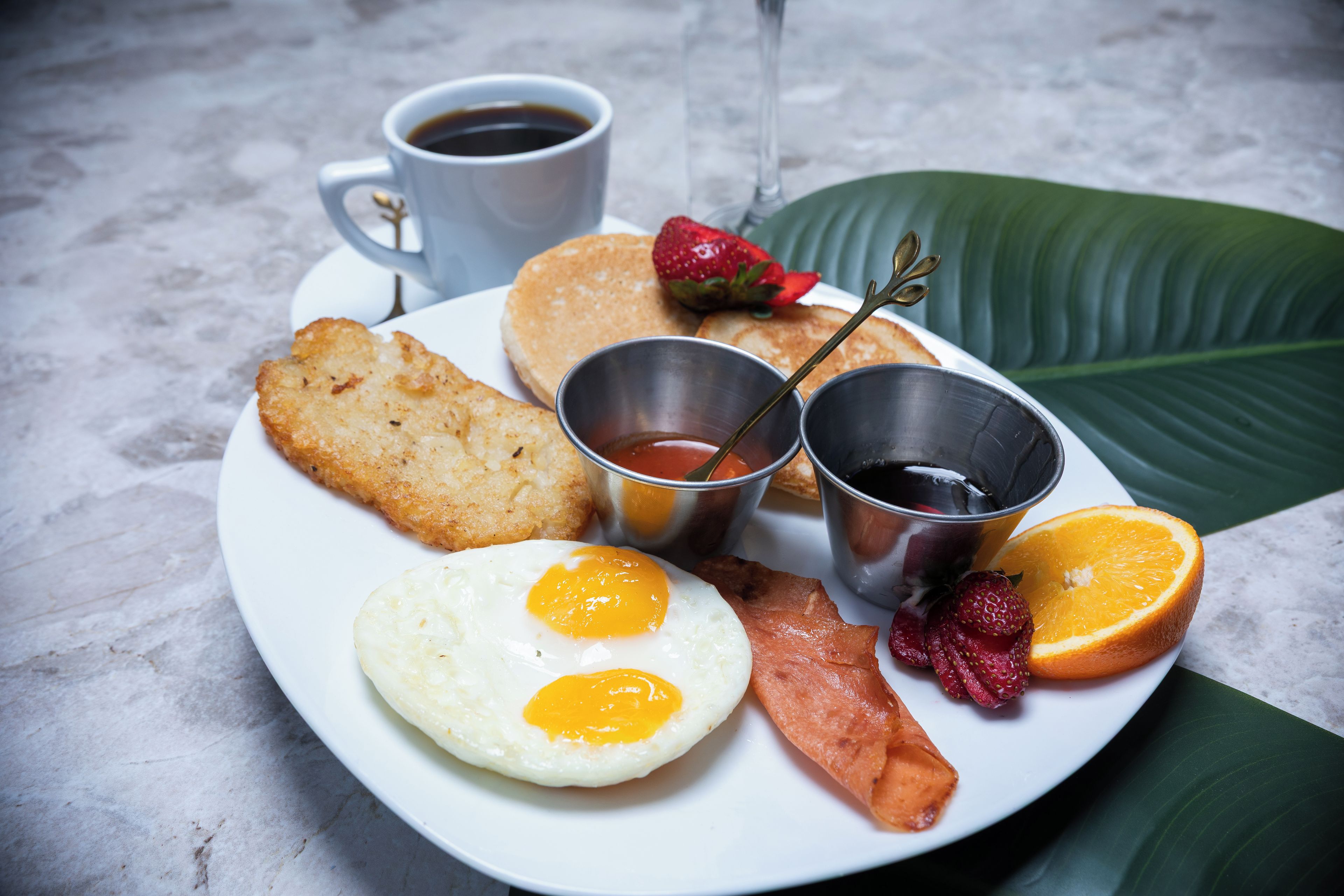 A plate of breakfast food including eggs, bacon, toast, and fruit.