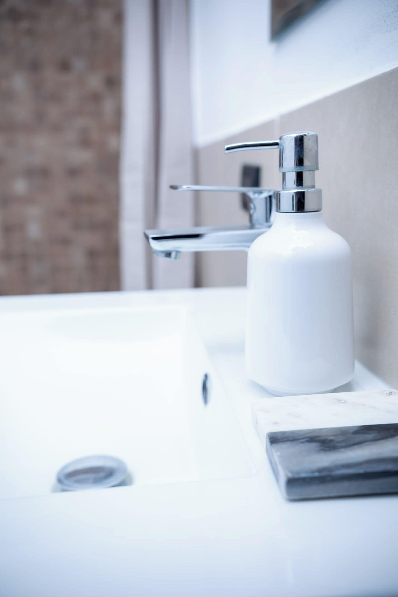 A bathroom sink with a chrome faucet and a soap dispenser.