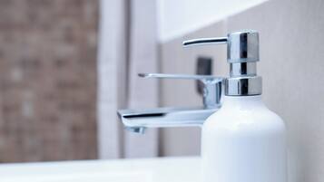 A bathroom sink with a chrome faucet and a soap dispenser.