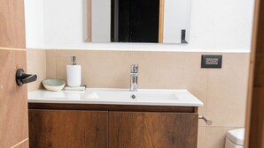 Ein Badezimmer mit einem Holzkonsolentisch, einem weißen Waschbecken, einem Spiegel und einer Toilette.