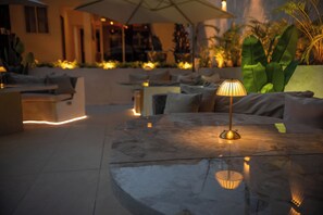 Zona relax all'aperto con tavolino, sedute imbottite e un ombrellone grande.