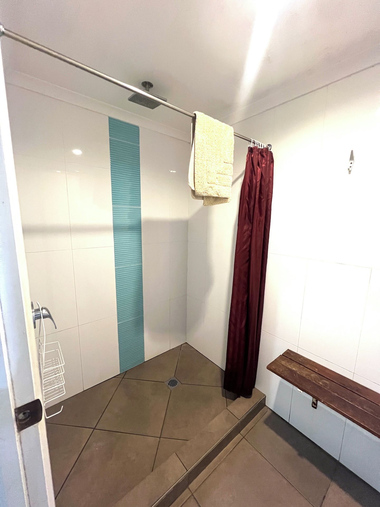 A shower area with a glass door, a towel hanging on a rack, and a bench.