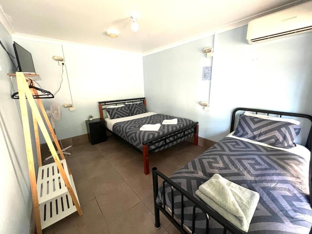 Una habitación con dos camas, televisión y aire acondicionado.