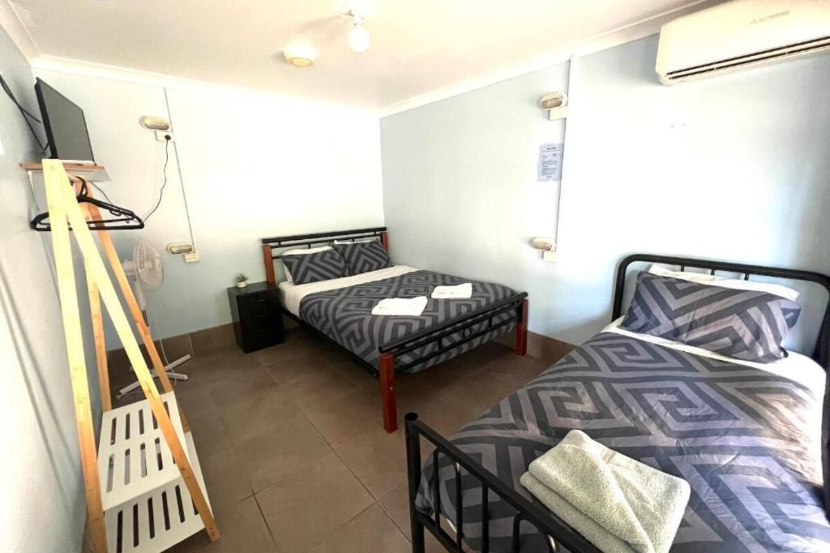 A room with two beds, a TV, and an air conditioner.