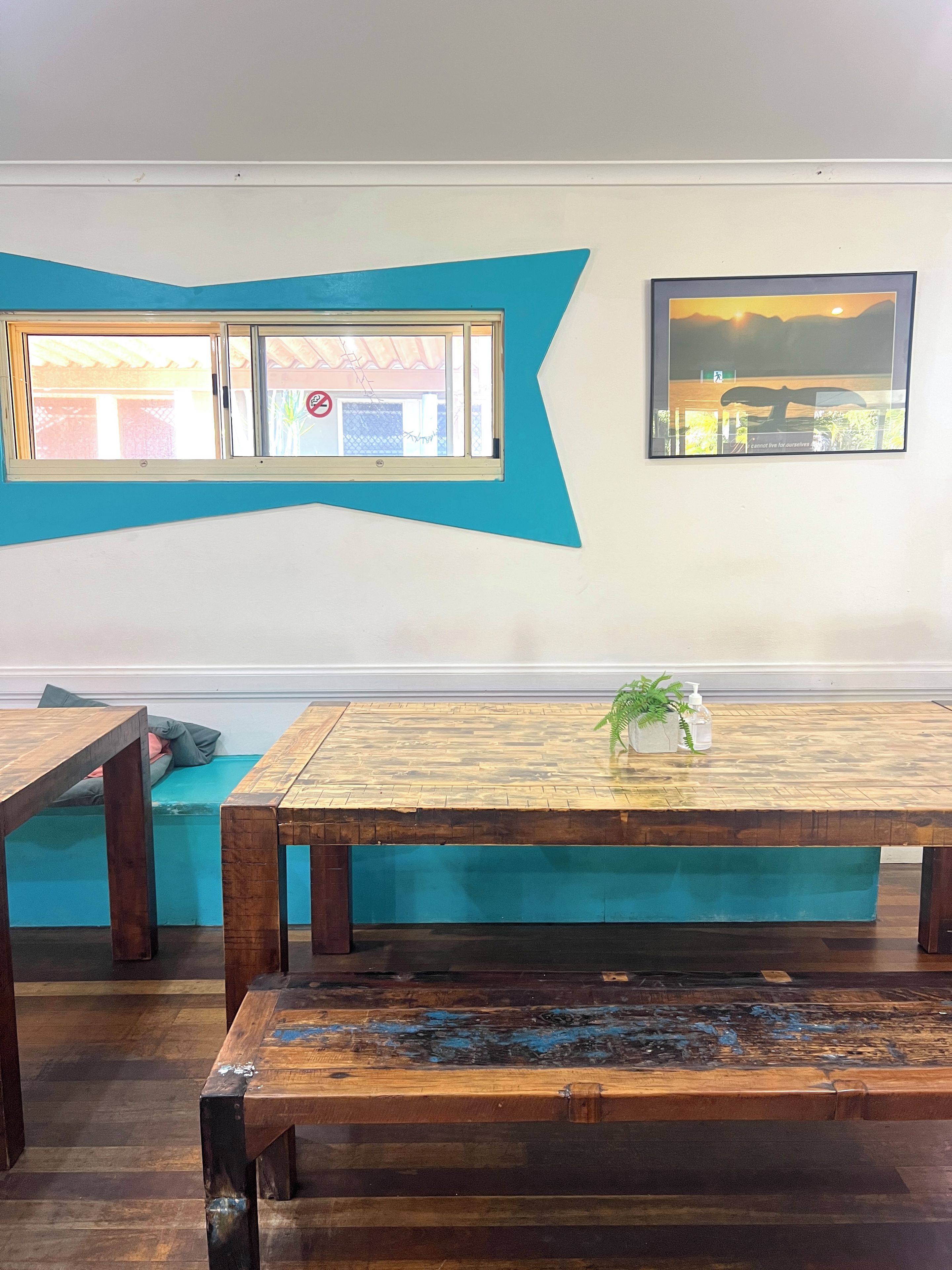 Een kamer met een houten tafel, een bankje en een muur met een blauw ontwerp en een inlijsting foto.