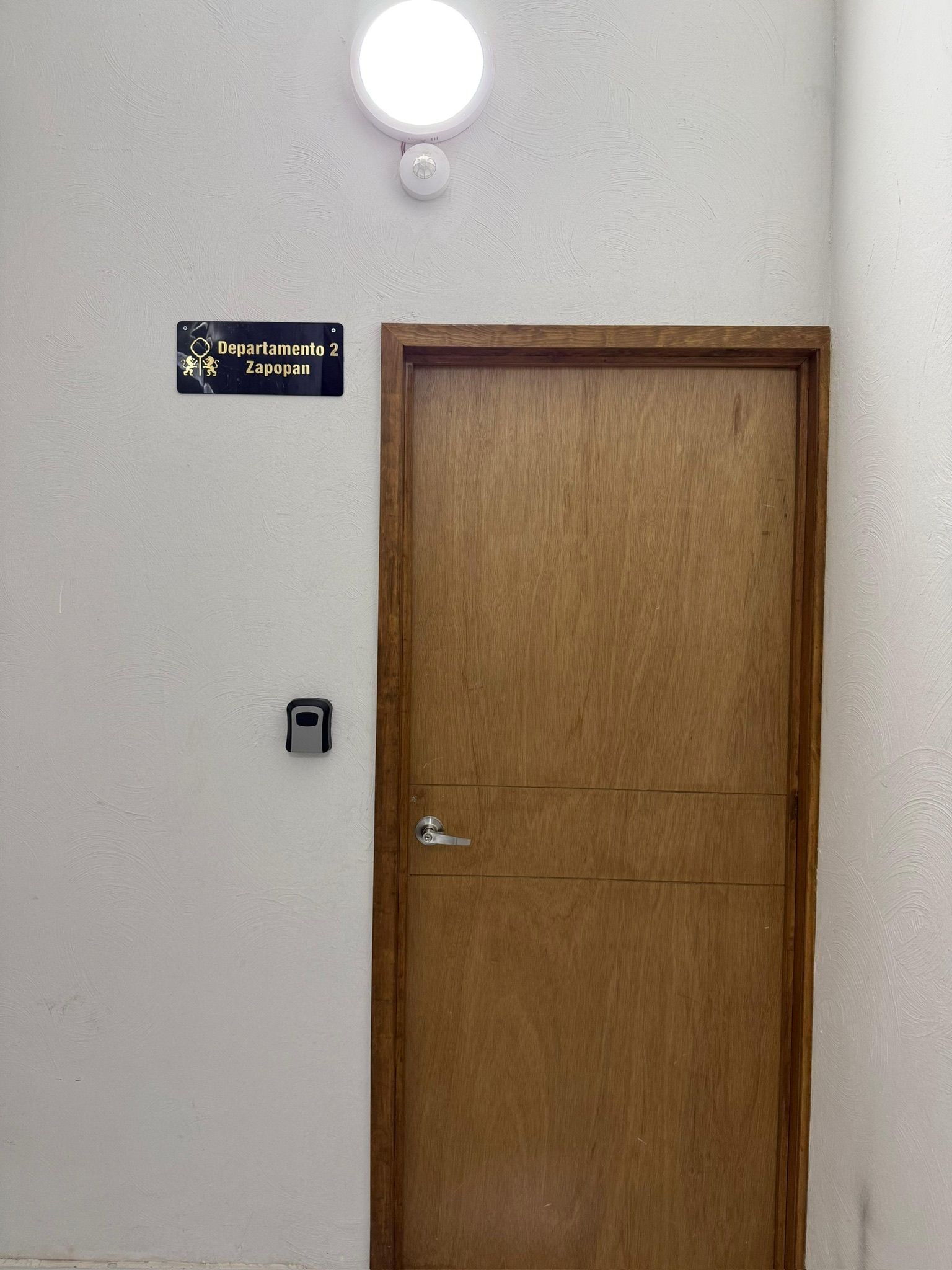 Une porte en bois, au-dessus de laquelle est affichée une plaque indiquant « Departamento 2, Zapopan ».