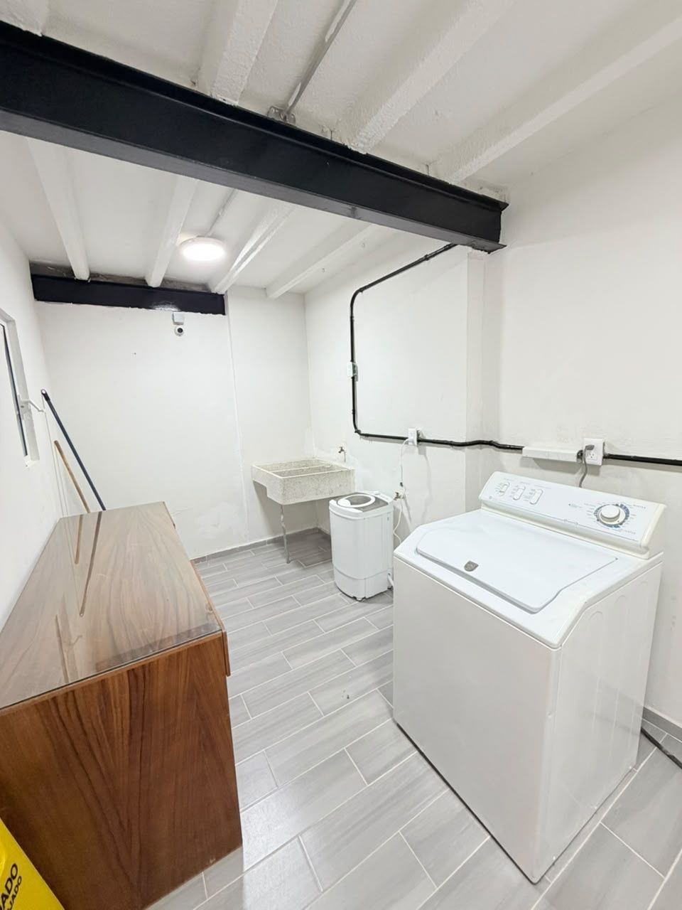 Un lavadero con lavadora, lavabo y un armario de madera.