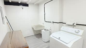 Un lavadero con lavadora, lavabo y un armario de madera.