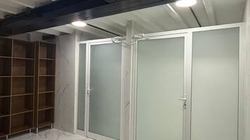 A room with a marble floor, a wooden shelving unit, and a set of frosted glass doors.