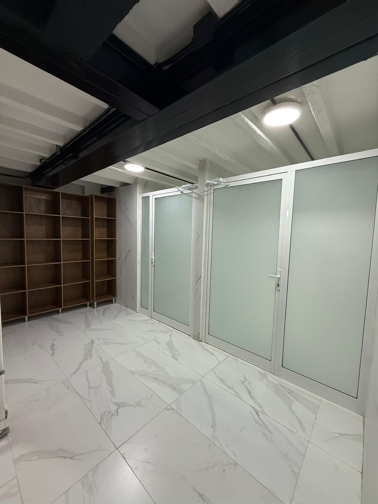 A room with a marble floor, a wooden shelving unit, and a set of sliding doors.