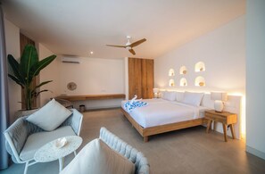 A modern hotel room with a large bed, two seating areas, a ceiling fan, and wall-mounted lighting. - Kona Resort Pererenan F (Badung)