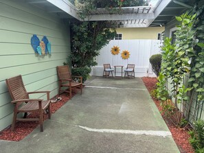 A patio with wooden chairs and a table, surrounded by a concrete floor and a low wall. -     Cozy 3BR Monterey Retreat – Close to Beach & Attractions (Monterey)
