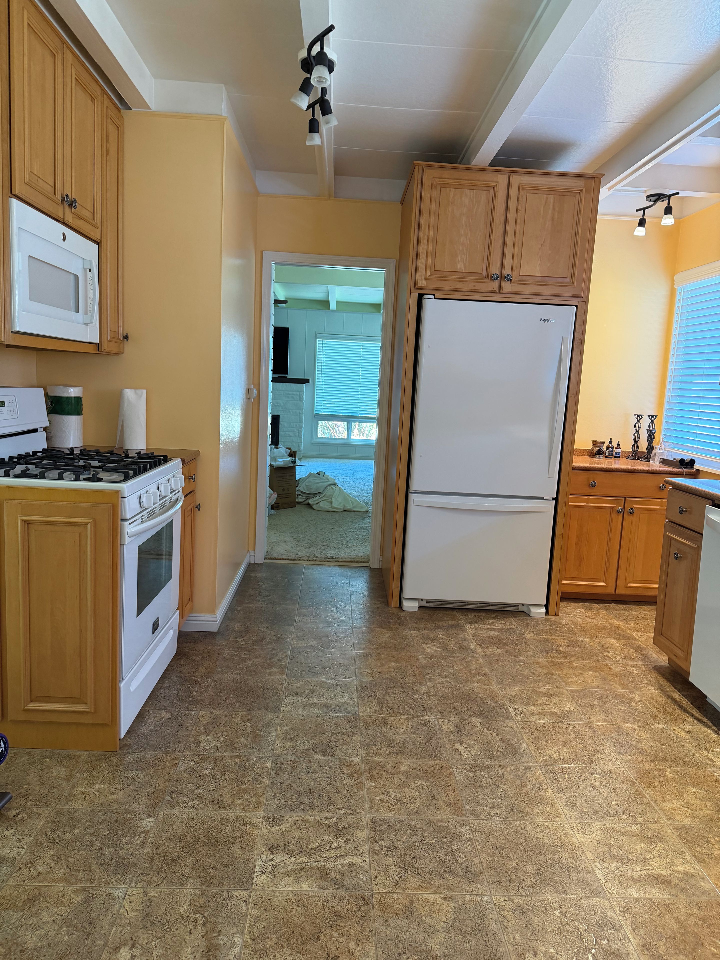 A kitchen with wooden cabinets, a white refrigerator, a stove, and a microwave.