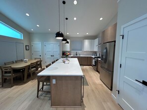 A modern kitchen with a central island, wooden flooring, and stainless steel appliances. - Ravens Rest - a Modern Stay in Midtown Anchorage. (Anchorage)