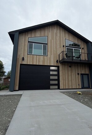 A modern two-story house with a black garage door, large windows, and a balcony. - Ravens Rest - a Modern Stay in Midtown Anchorage. (Anchorage)