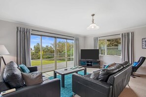 Ein Wohnzimmer mit einer Couch, einem Couchtisch, einem Fernseher und einem Sessel.