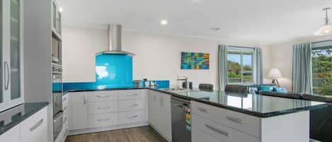 Cozinha moderna com armários brancos, painel azul e máquina de lavar louça embutida.