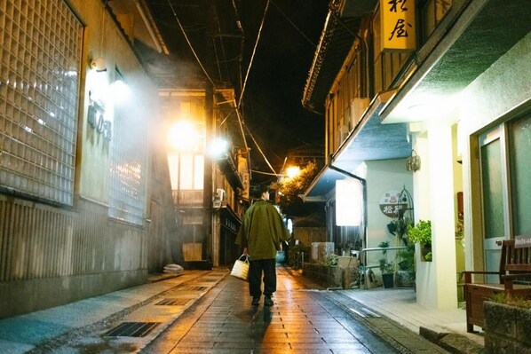 A narrow alleyway with traditional buildings, a person walking, and a shop with a sign.