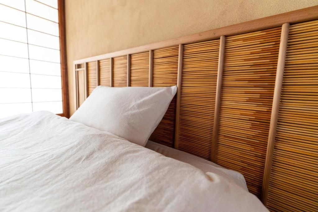 Ein Bett mit hölzernem Kopfteil und weißer Bettwäsche.