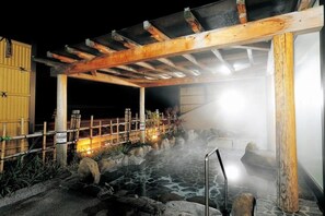 Un onsen japonés tradicional con estructura de madera, tina de piedra y ambiente brumoso.