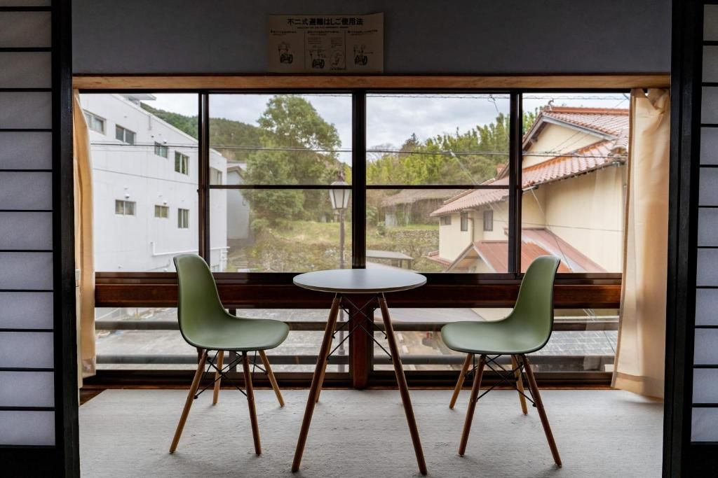 A room with a large window, two chairs, a small table, and a wooden bench.