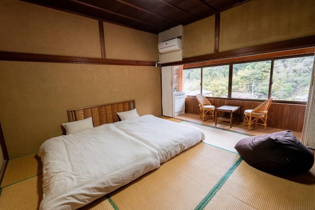 Une pièce avec un lit, une petite table, deux chaises et une vue par la fenêtre.
