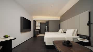 Una habitación de hotel moderna con cama, mesita de noche, televisor y una pequeña mesa con un frutero.