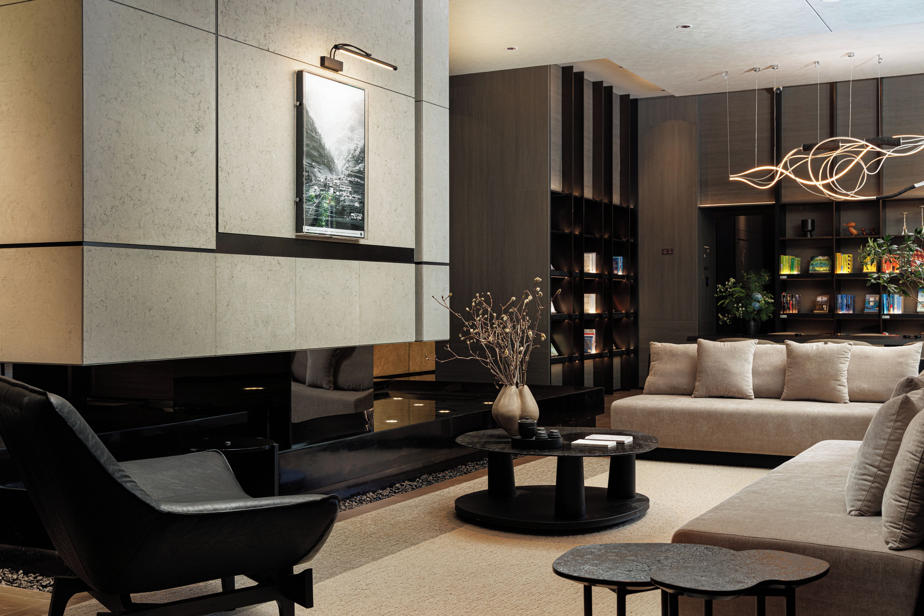 A modern living room with a sofa, armchair, coffee table, and bookshelves.