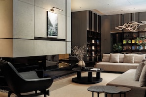 A modern living room with a sofa, armchair, coffee table, and bookshelves.